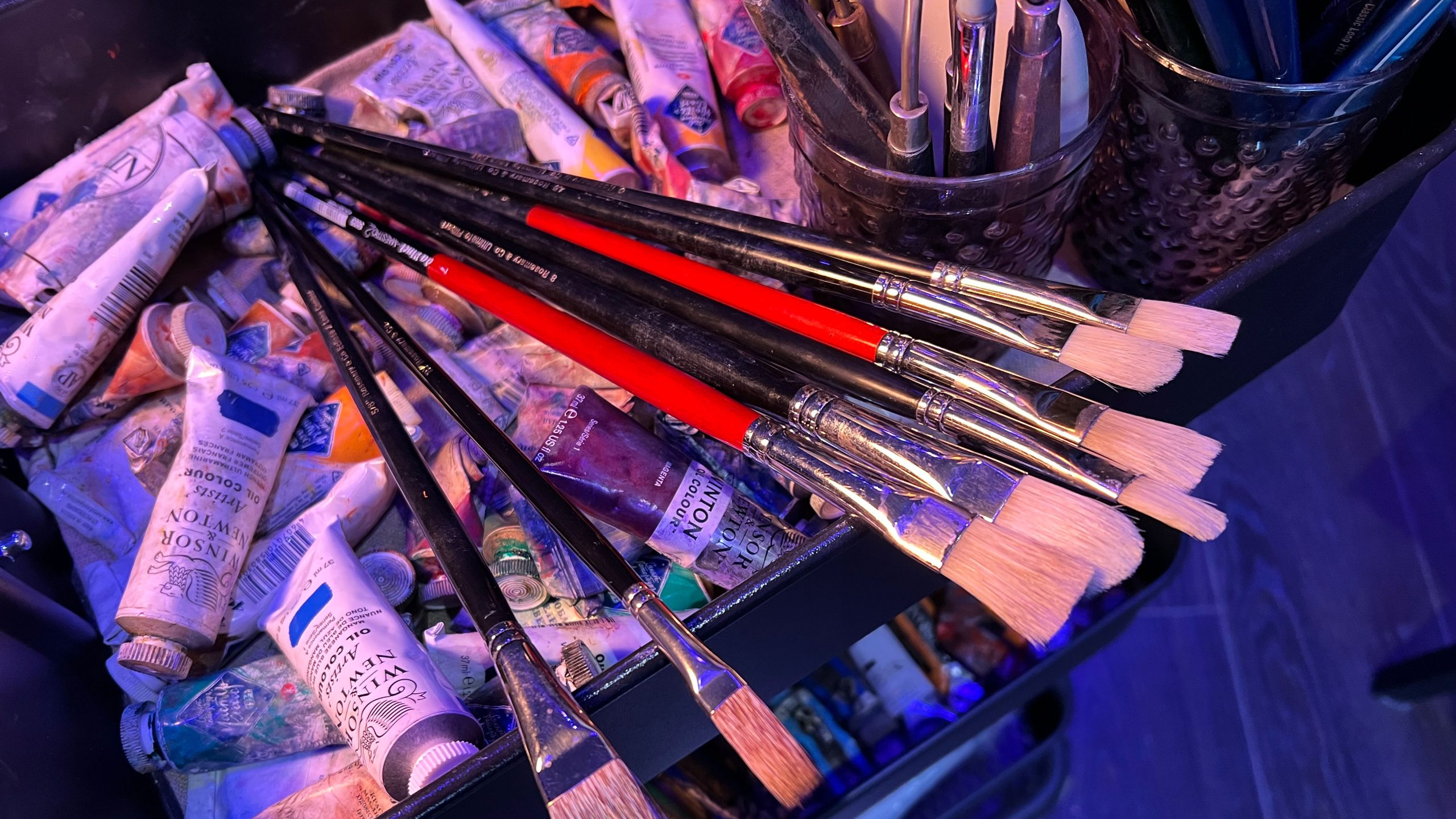 Brushes set against the background of oil paint tubes