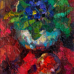 Blue Viola flowers and a ripe apple gracefully arranged on a striking red backdrop